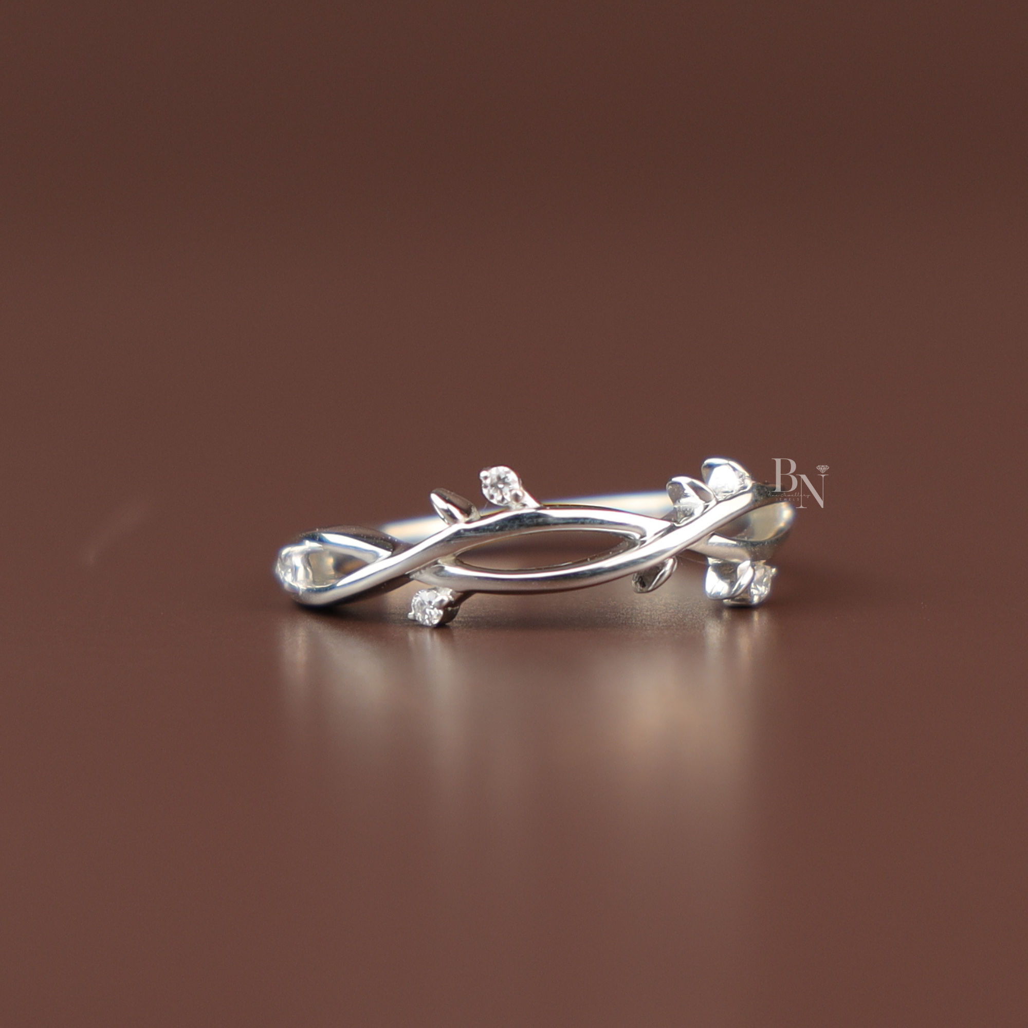 Delicate nature inspired branch engagement ring in solid white gold featuring an organic twisting twig design and small round brilliant cut lab grown diamond leaves flush set along the whimsical botanical band.