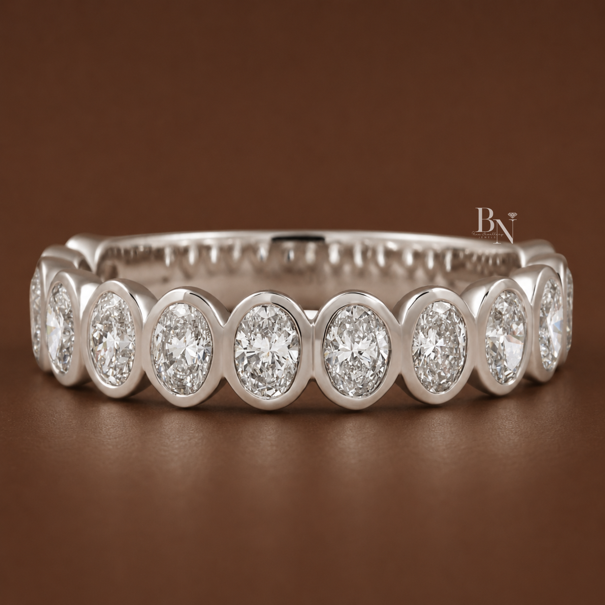 1.16 carat total weight oval cut lab diamond three quarter eternity band. Crafted in brilliant white and yellow gold featuring a secure 4.4mm wide individual bezel setting. Perfect fine jewelry bridal stacking ring or modern anniversary gift.