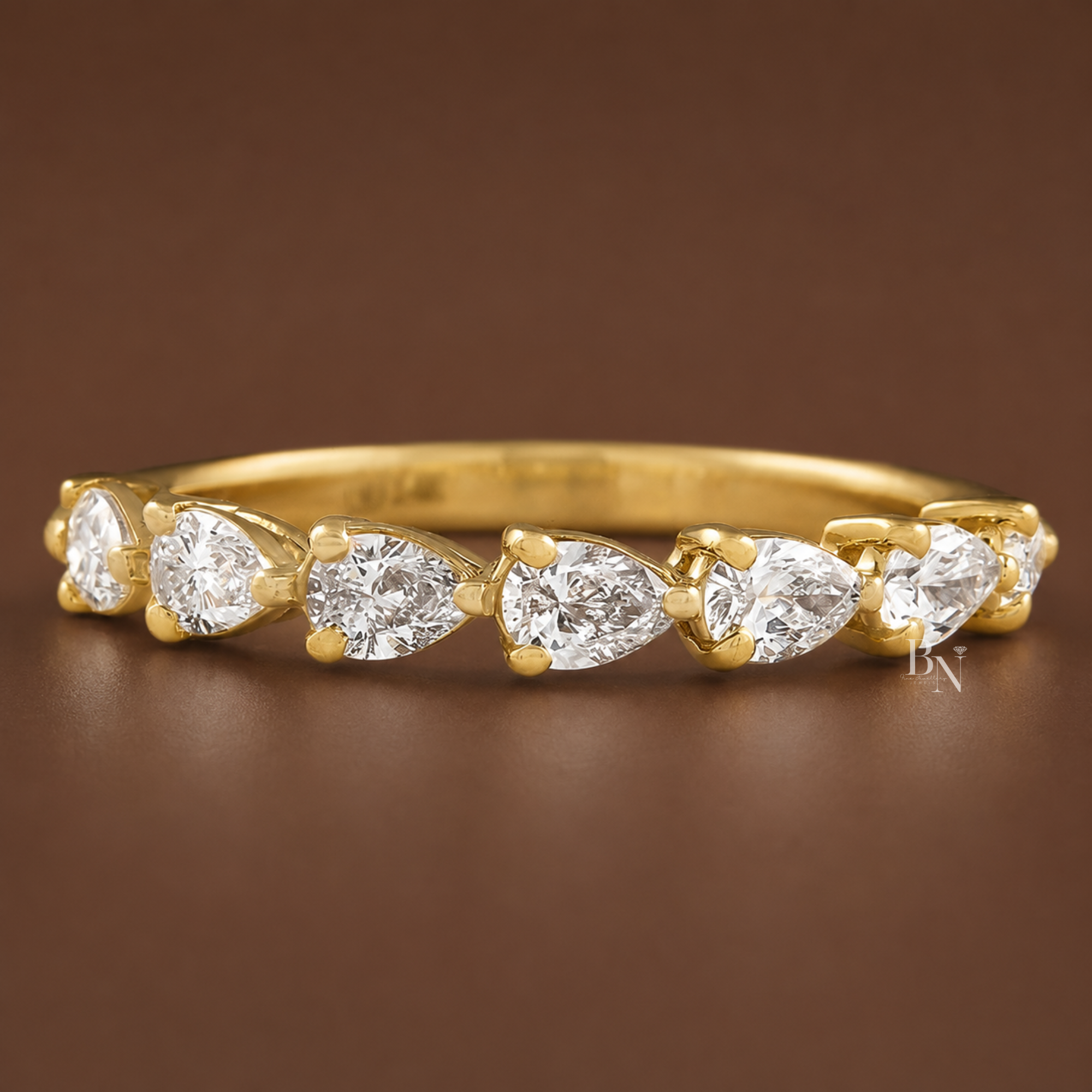 0.60 carat total weight pear cut lab diamond halfway wedding band. Crafted in 14K gold featuring a unique east-west prong setting and a 2.85mm band width. A luxurious fine jewelry piece perfect for a bridal stack or elegant anniversary gift.