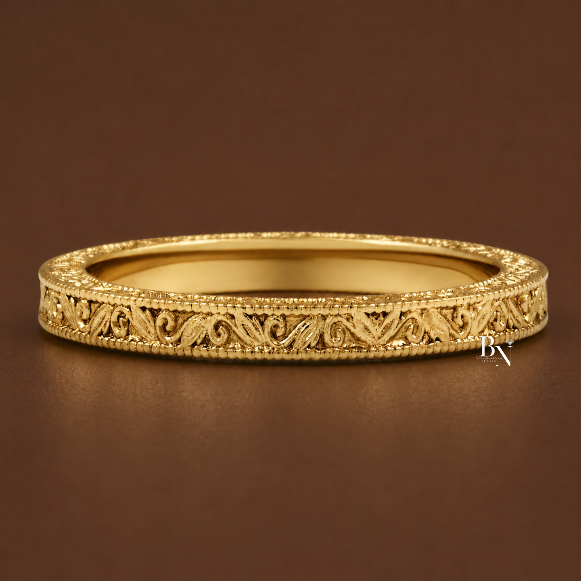 Vintage inspired 2.2mm solid gold wedding band. Features intricate scroll engraving on three sides with delicate milgrain edges. This handmade bridal stacking ring is shown on hand and isolated in white, yellow, and rose gold.
