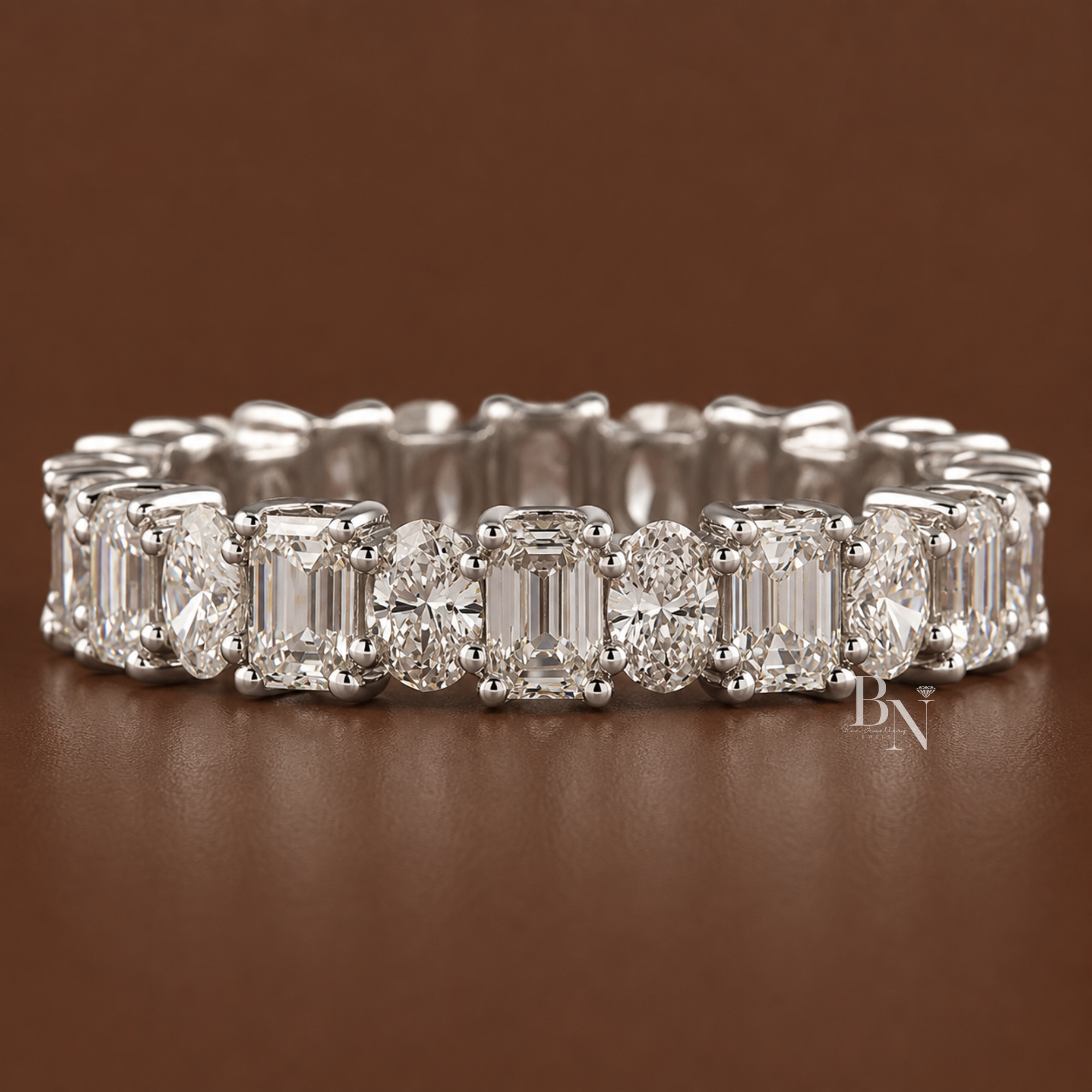 Alternating oval and emerald cut lab diamond full eternity band in a u-shape prong setting. Showcasing 2.94 total carats on a 4.21mm solid gold band, this luxury bridal stacking ring is displayed styled with engagement rings and isolated in multiple gold tones.