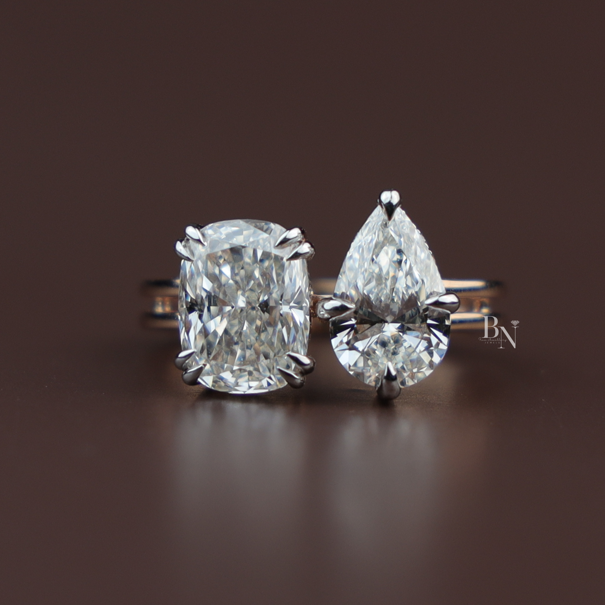 Toi et Moi engagement ring featuring a cushion cut and pear cut lab diamond, bypass setting in high polish gold, unique modern two-stone wedding ring.