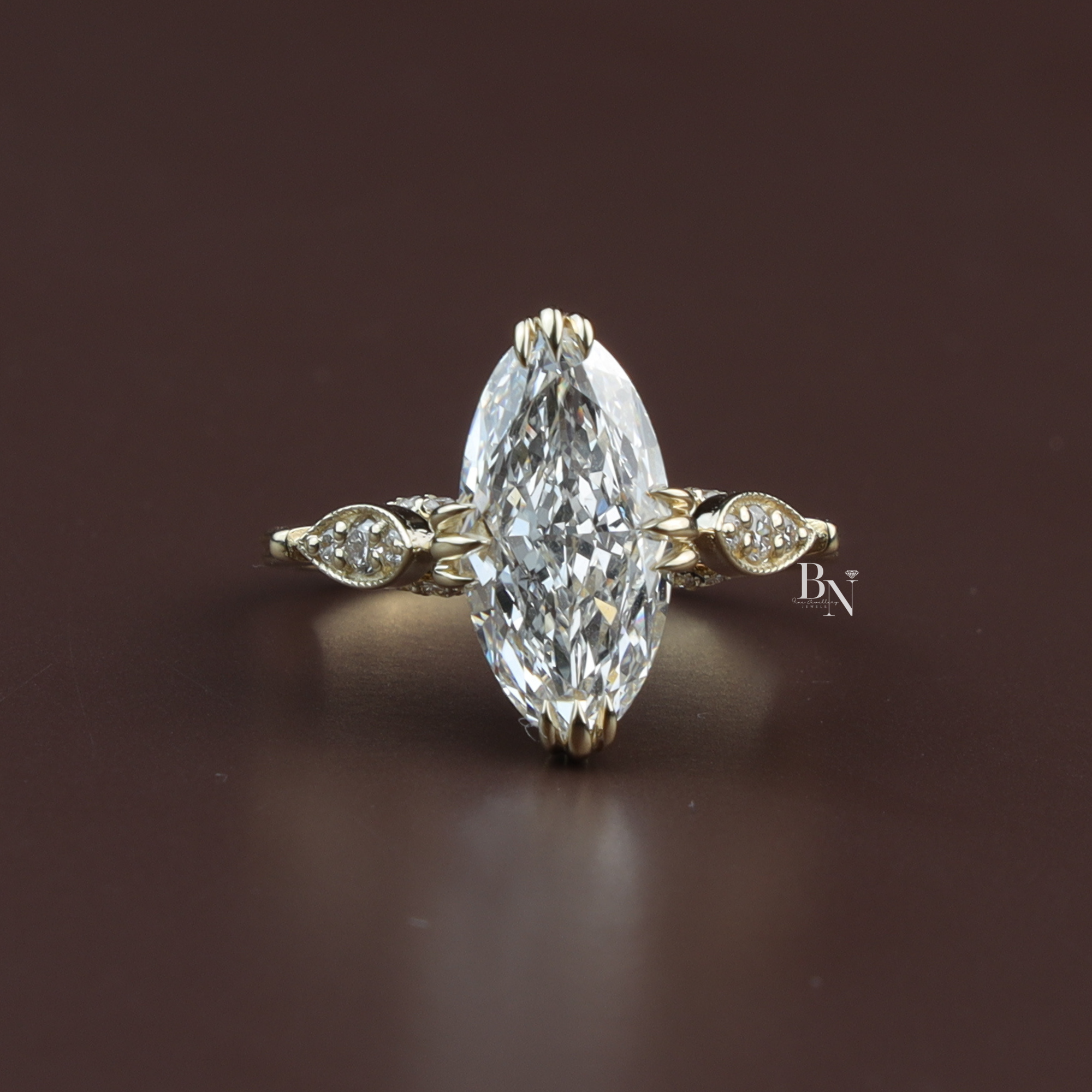 Moval cut lab diamond engagement ring in 14k yellow gold featuring a unique vertical petal basket setting and delicate marquise-style accent stones on the band.
