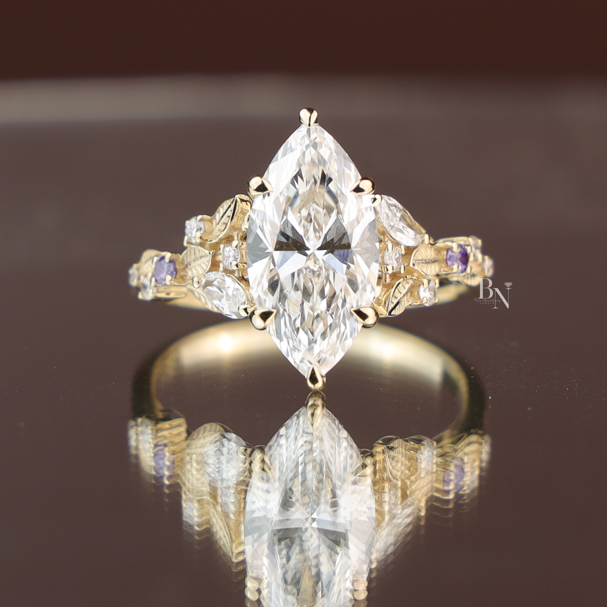 3 carat appearance marquise cut lab diamond engagement ring in yellow gold tone. Features a stunning six prong center stone on a botanical leaf band accented with white and purple side stones, offering handcrafted fine jewelry for a romantic bride.