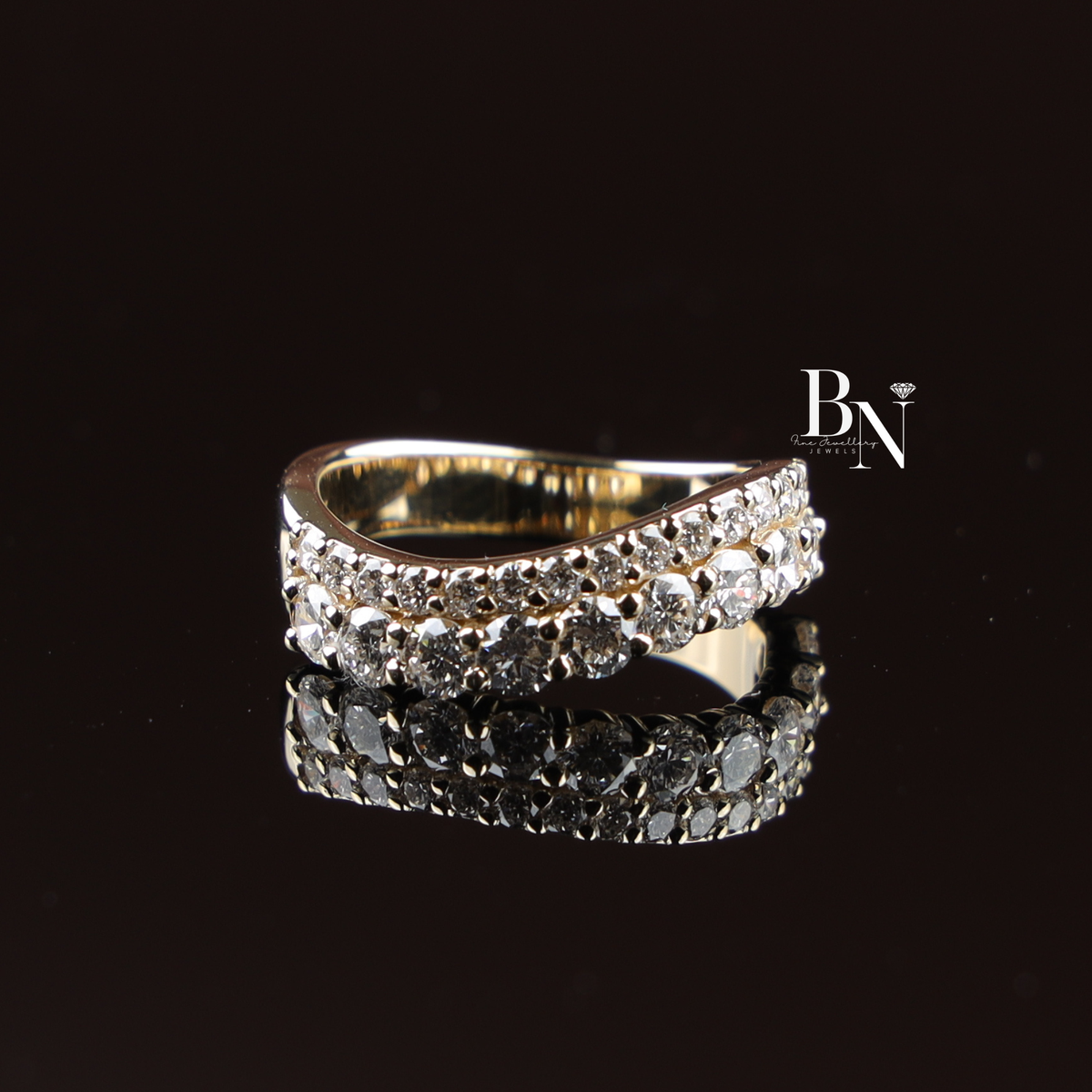 Front view of a two-row curved lab grown diamond band in yellow gold, featuring 1.5 ctw of sparkling round brilliant cut diamonds set in a wavy contoured half-eternity style on a natural wood surface.