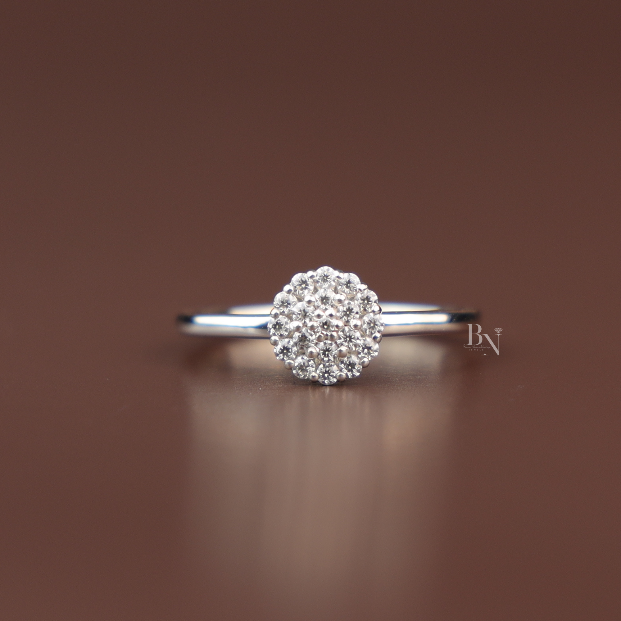 Close up view of a dainty 0.20 ctw round brilliant cut lab grown diamond composite cluster engagement ring inside an elevated white gold prong basket over a plain polished minimalist band.