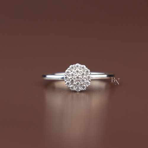 Close up view of a dainty 0.20 ctw round brilliant cut lab grown diamond composite cluster engagement ring inside an elevated white gold prong basket over a plain polished minimalist band.