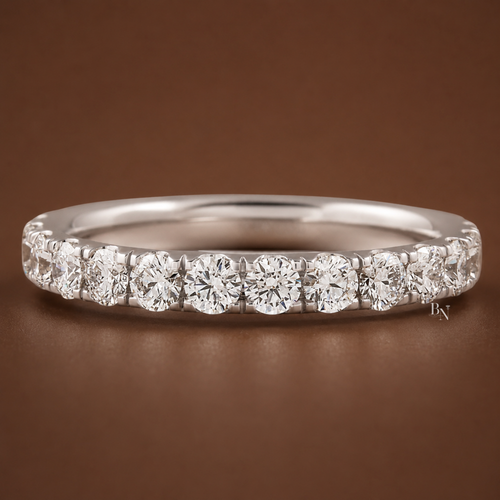 Angled front view of a white gold pave lab diamond eternity band resting on a dark brown background.