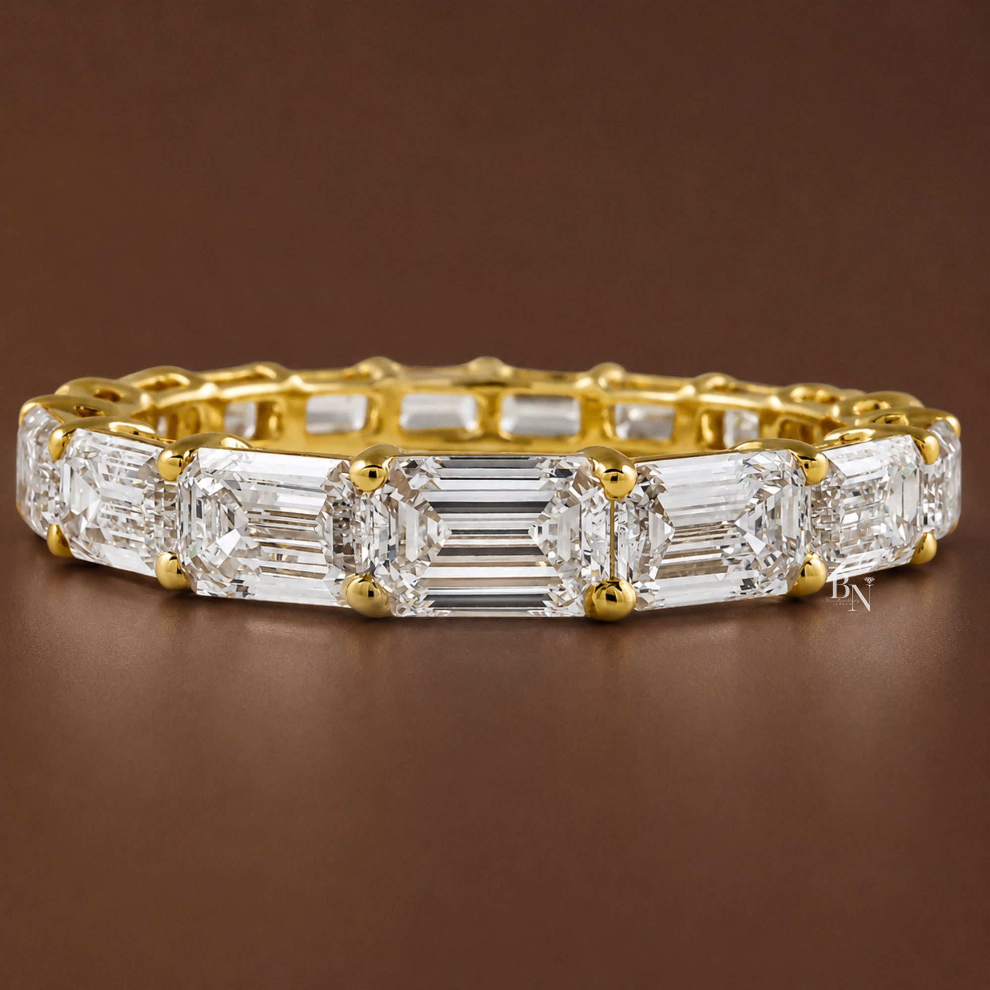 Front view of a 14K yellow gold eternity band featuring east-west set emerald-cut lab diamonds that taper in size toward the edges.