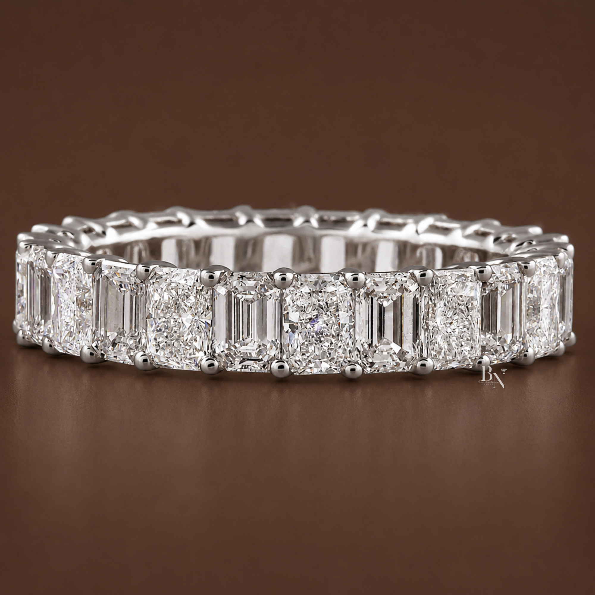 Face-up angled view of a white gold full eternity band featuring an alternating pattern of emerald and radiant-cut lab-grown diamonds set in open airline baskets.
