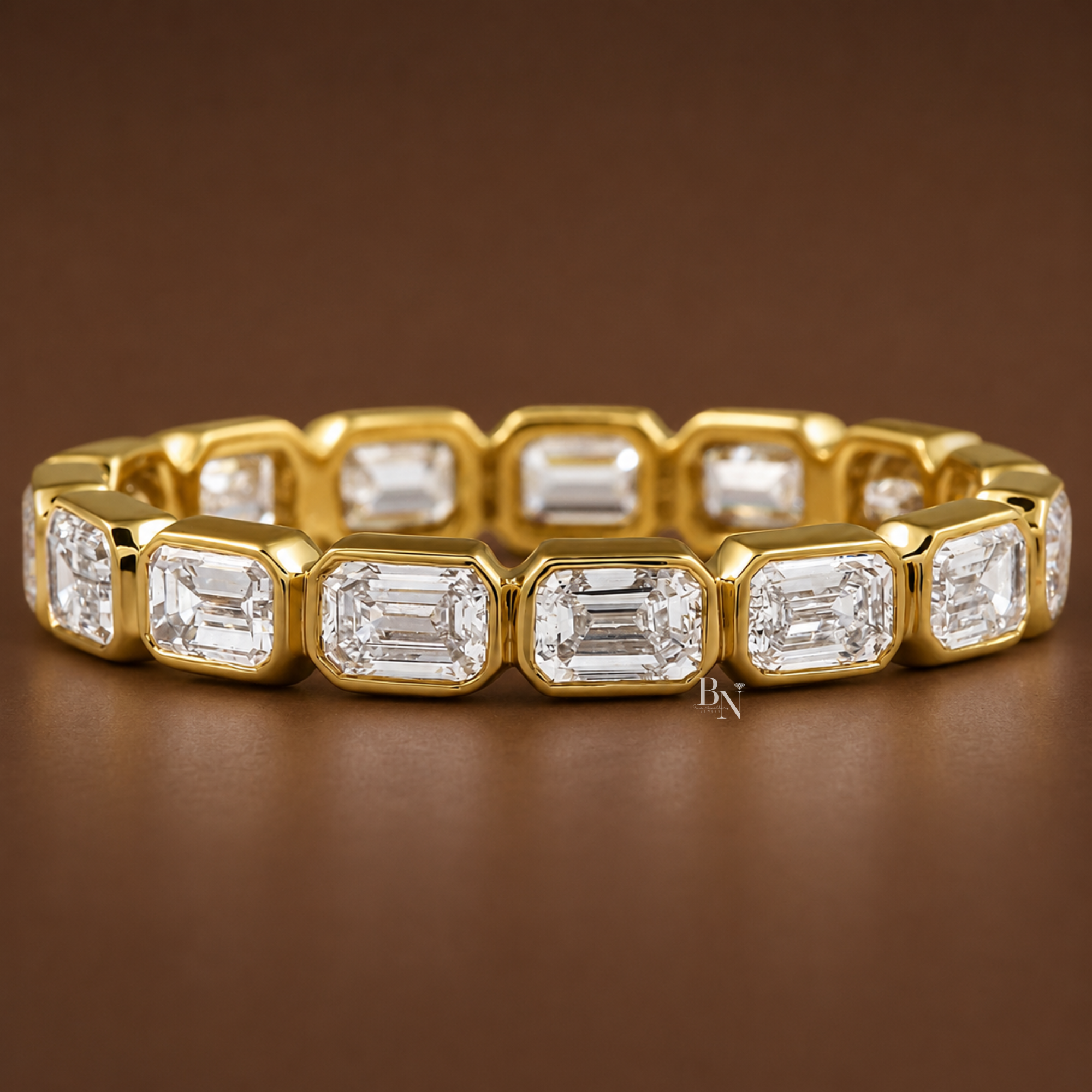 Front face-up view of a yellow gold full eternity band featuring horizontal emerald-cut lab-grown diamonds secured in a continuous bezel setting.