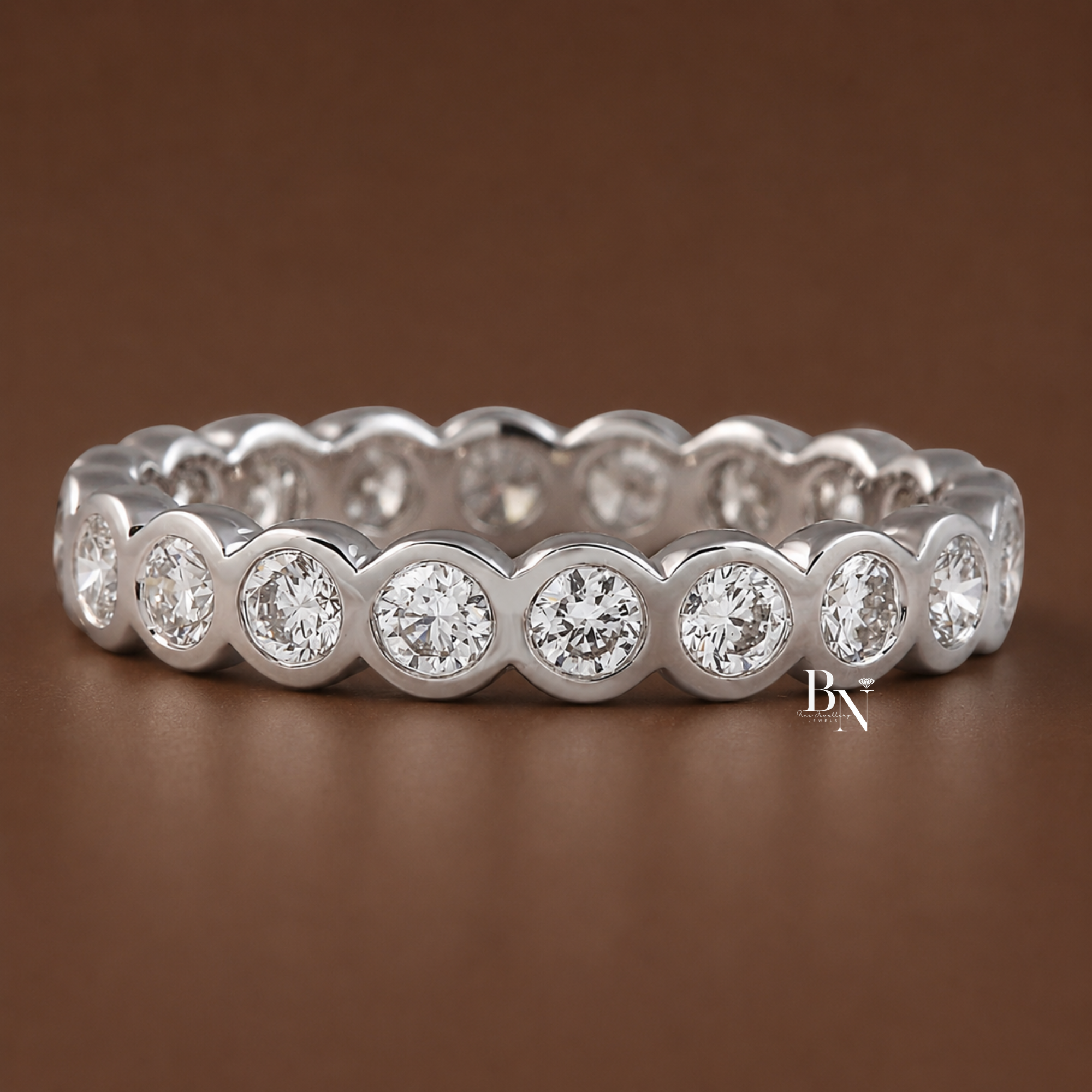Close-up on-hand view of a white metal 3.4mm full eternity band featuring round brilliant lab-grown diamonds secured in a continuous bezel setting.