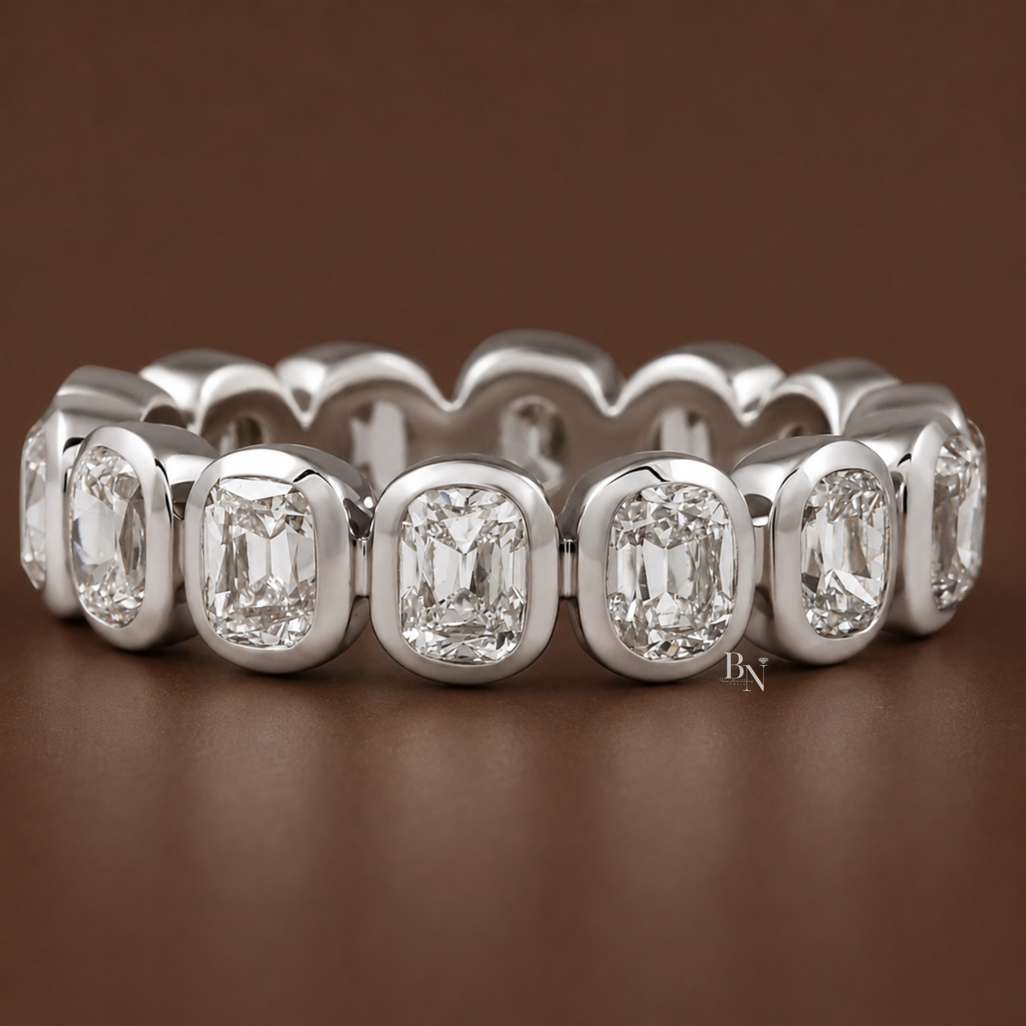 Angled front view of a white gold antique cushion cut bezel eternity band resting elegantly on a dark brown background.