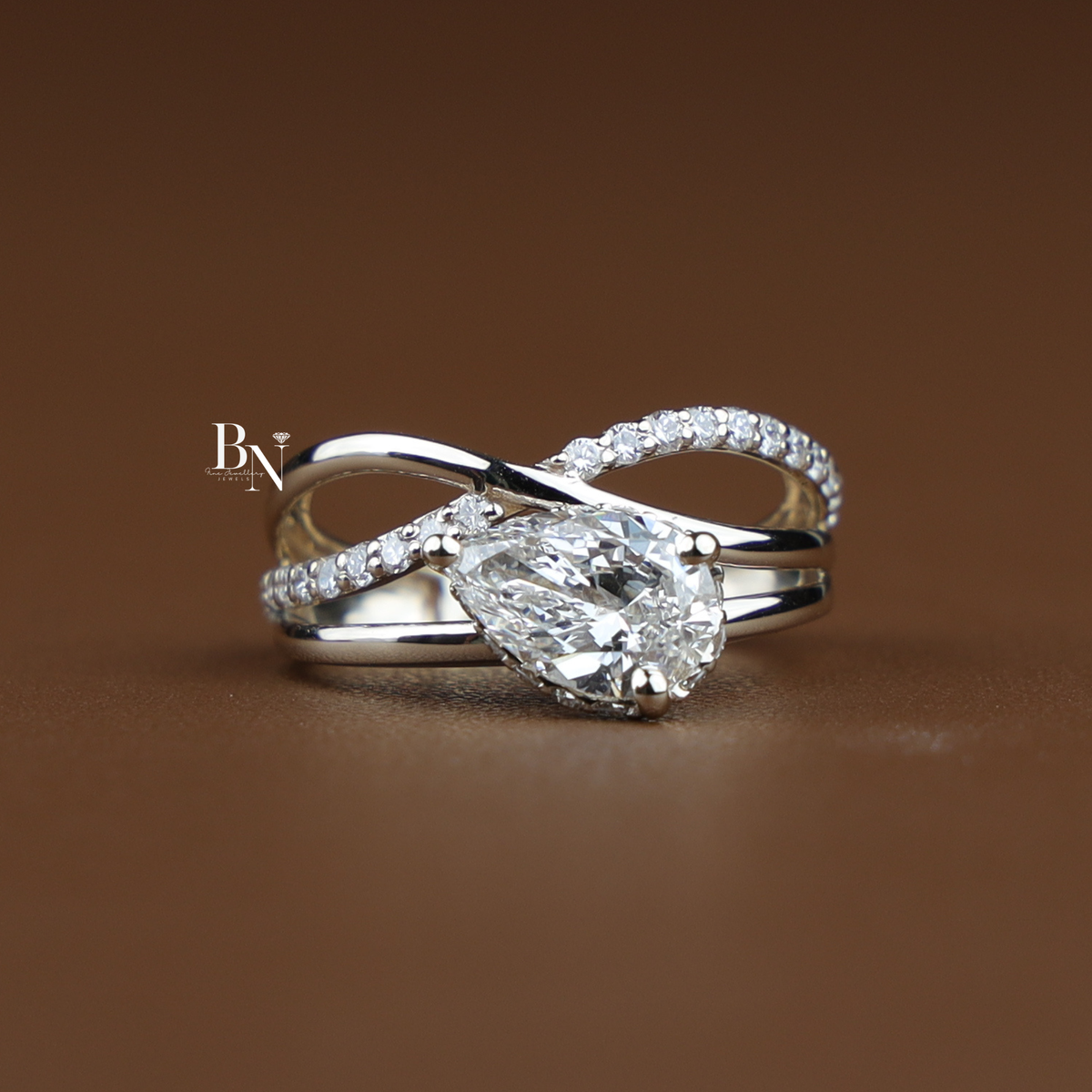 Back gallery view of a Gold-tone engagement ring showing the architectural criss-cross split-shank band wrapping beneath the pear-cut diamond setting.