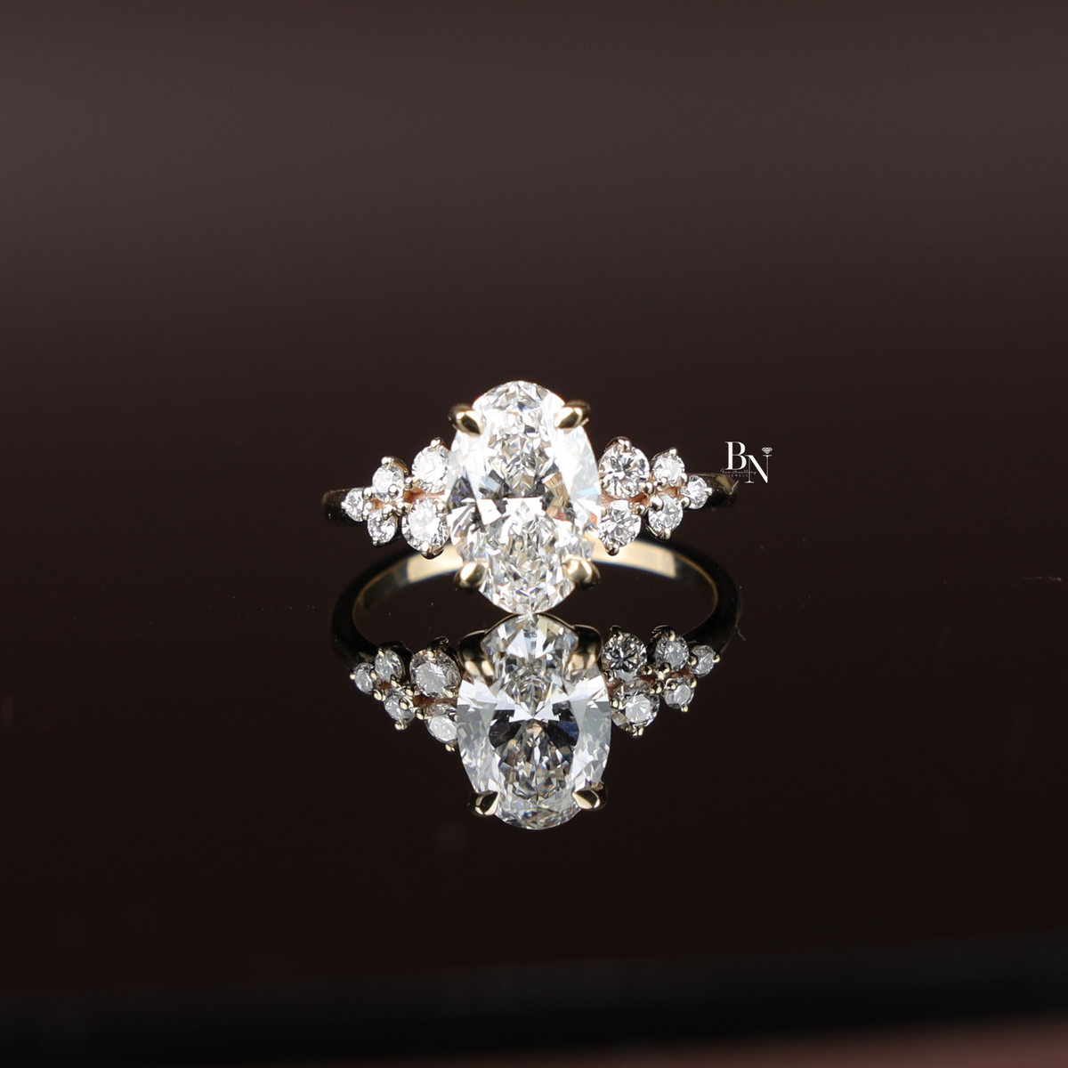 2 carat oval-cut lab-grown diamond engagement ring with cluster accent stones set in polished yellow gold band.