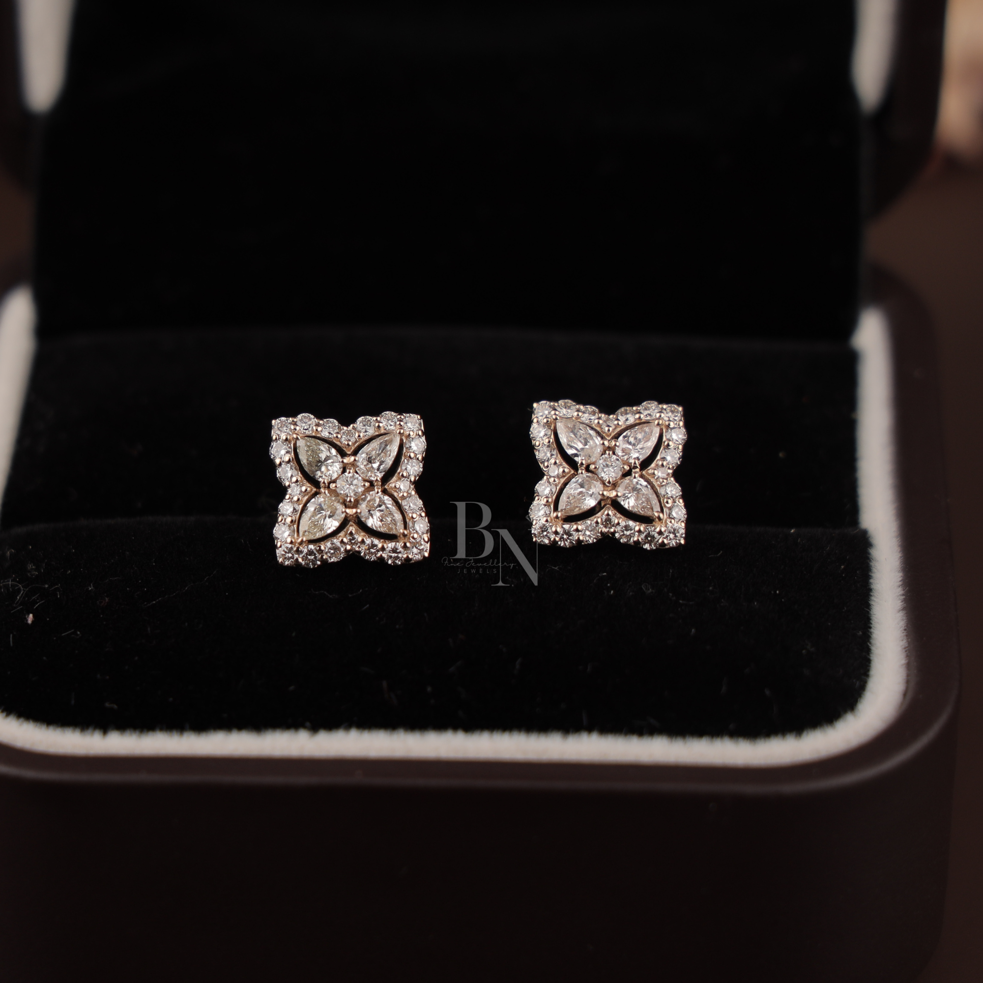 Close-up of 1.75 ctw floral moissanite earrings in rose gold with intense rainbow fire and brilliance. The unique pear petal cluster and outer cushion halo are designed to maximize sparkle for a luxury, high-performance aesthetic.