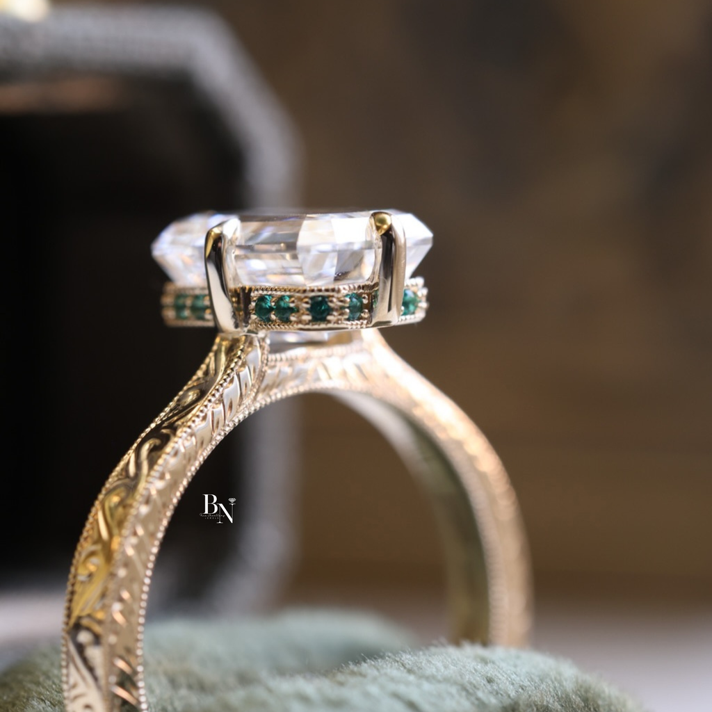 3.00 carat emerald cut lab diamond engagement ring in 14k yellow gold with intricate vintage filigree scrollwork on the band and a unique hidden emerald gemstone halo.