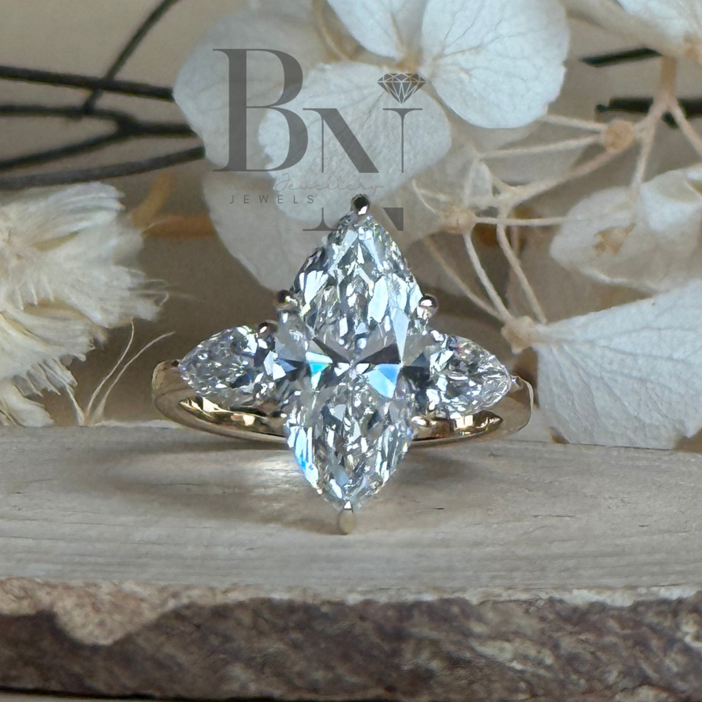 3 carat elongated marquise lab grown diamond engagement ring in 14k  gold three stone setting with pear side stones and a hidden halo detail shown from a front-facing angle on a neutral background to showcase Type IIa diamond brilliance.