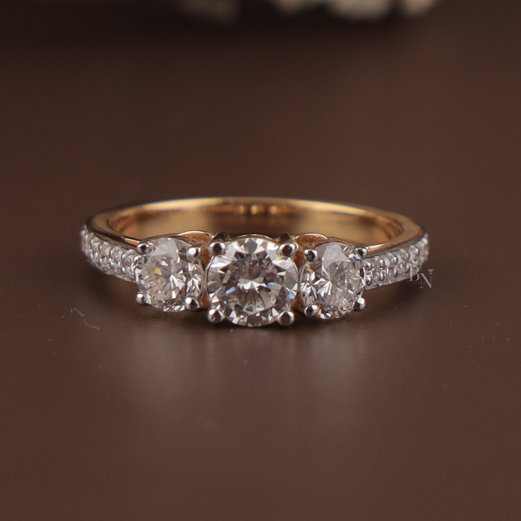 1.25 carat total weight three stone lab grown diamond engagement ring featuring three round brilliant center stones in white gold prongs on a 14k yellow gold pave-set diamond band showing white light return and crisp clarity.