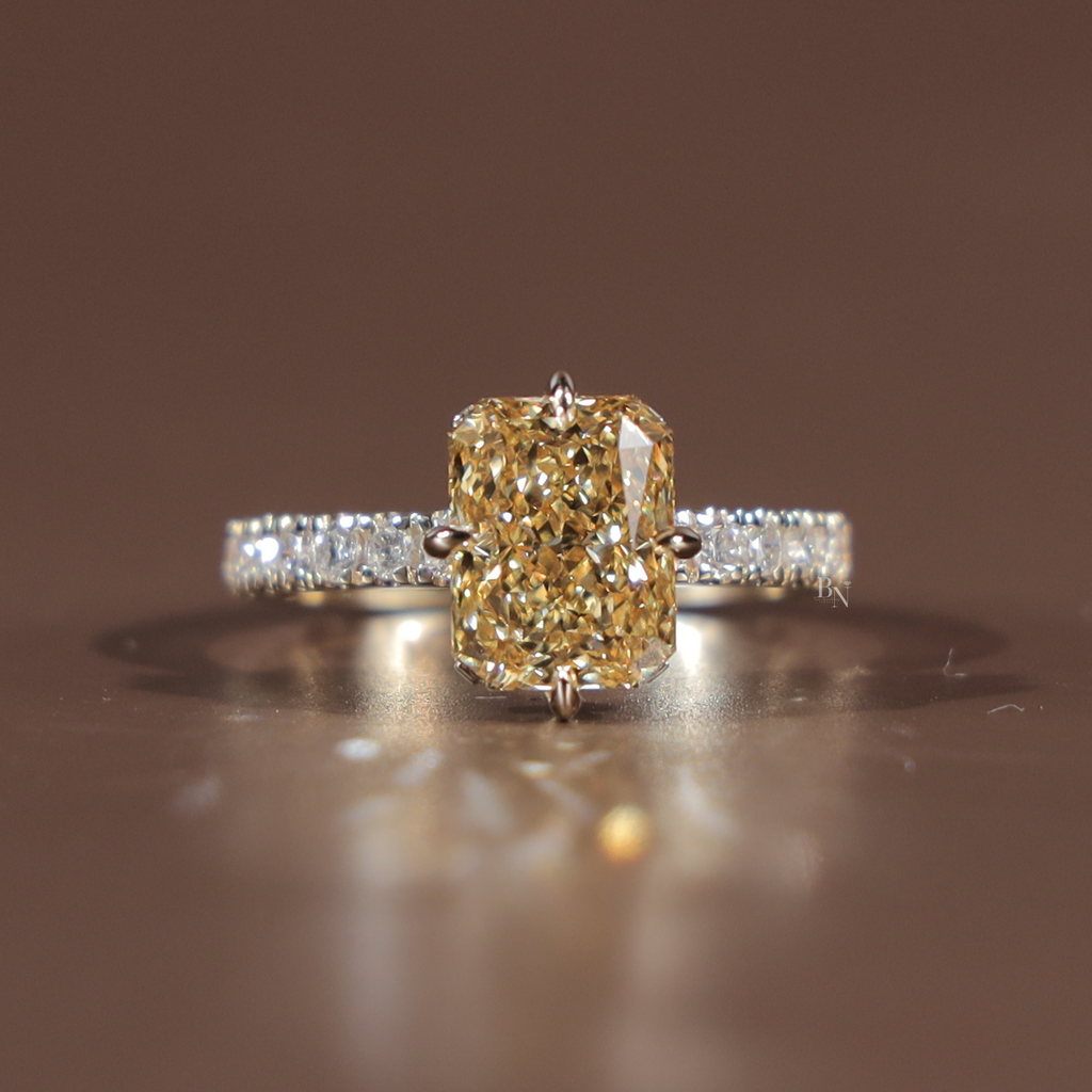 Side profile of a 3.5 carat elongated radiant cut fancy yellow lab grown diamond engagement ring featuring a sparkling hidden halo and a delicate white gold pave band with canary yellow diamond brilliance and Type IIa clarity.