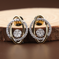 Pair of modern abstract stud earrings featuring interlocking 14k yellow gold and white gold oval bands with a center round lab grown diamond cluster and pave halo.