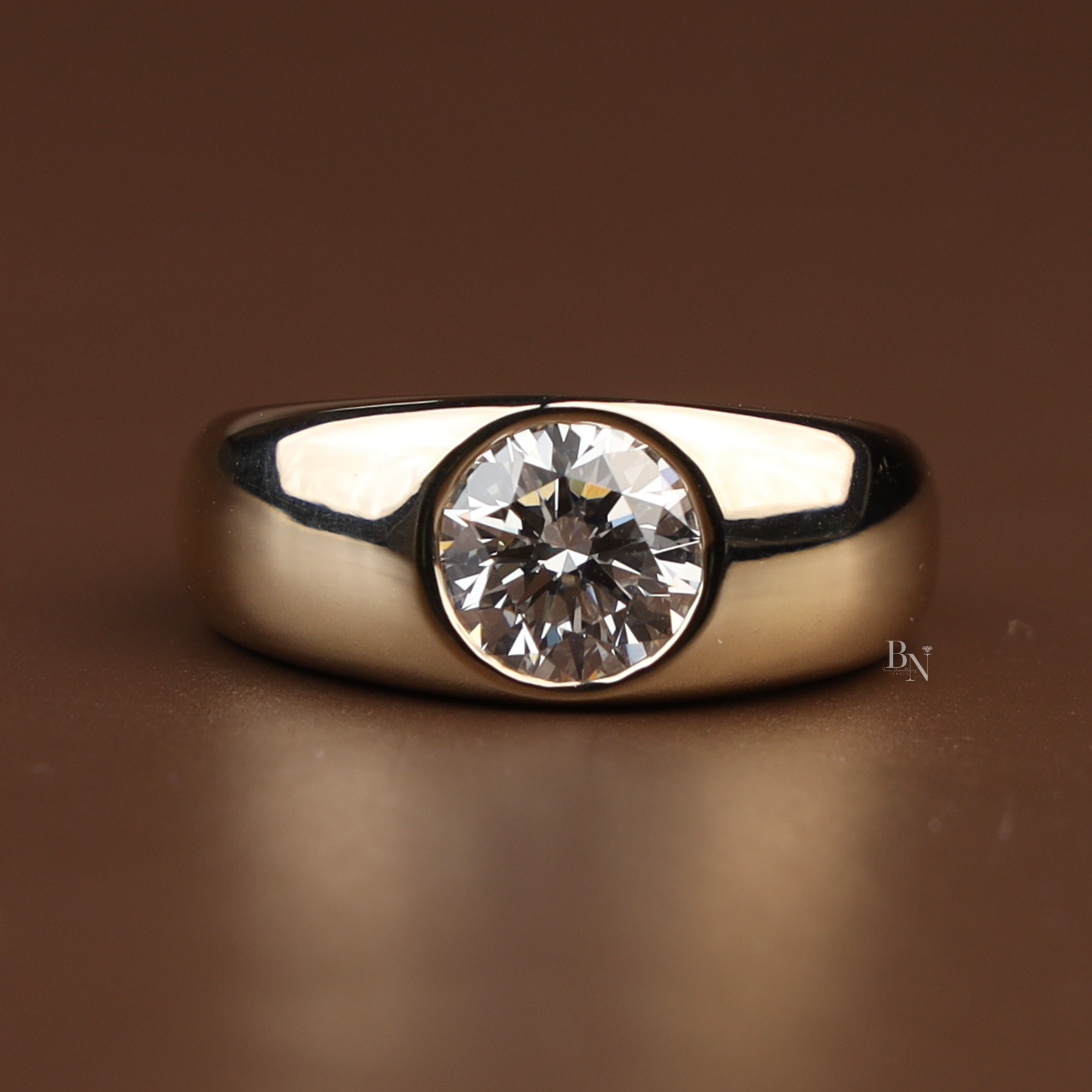 1.50 carat round brilliant cut lab grown diamond engagement ring in a secure bezel setting with a thick 14k yellow gold wide band showing high polish finish and modern minimalist design for a timeless proposal.