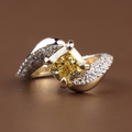Side profile of a 2 carat fancy yellow cushion cut lab grown diamond engagement ring featuring a unique bypass band pavé set with white diamonds in 14k gold.