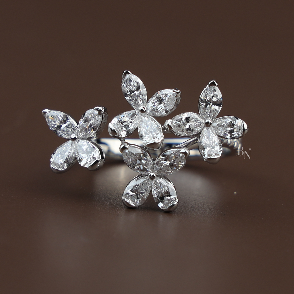 Top view of 2 carat total weight lab grown diamond butterfly ring featuring marquise cut diamonds in a cluster floral setting on a 14k white gold bypass band with pavé diamond accents worn on a hand with red nails.