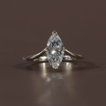 1.50 carat marquise cut lab grown diamond engagement ring in 14k white gold featuring a hidden halo under-setting and a polished tapered cathedral band shown on a hand and black silk background for luxury scale and detail.