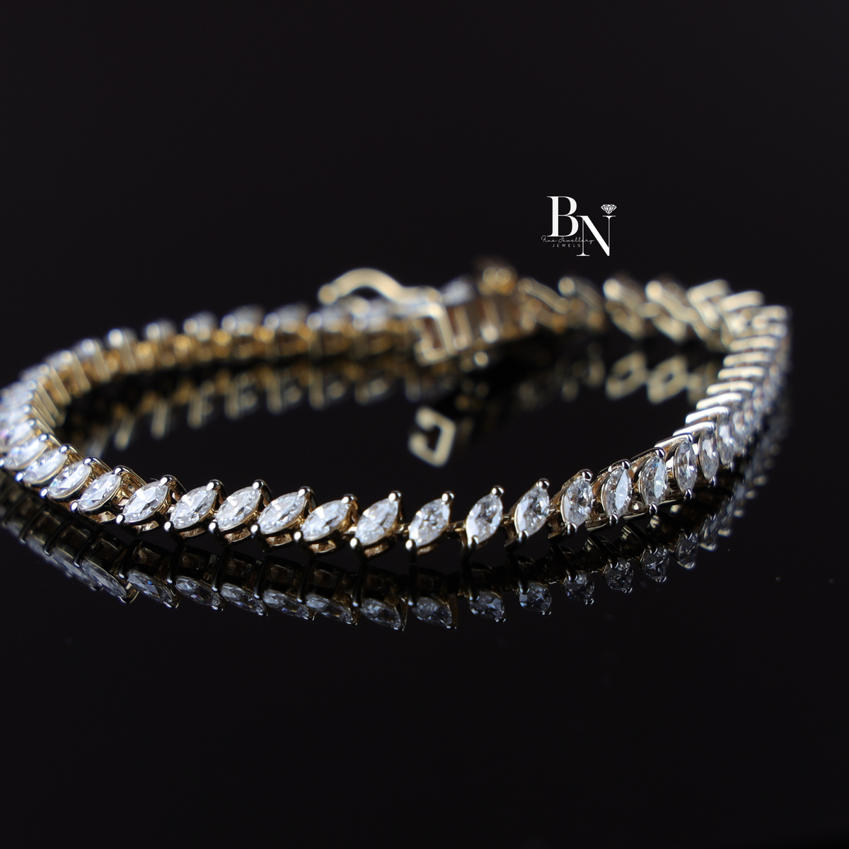 A 2.60 carat marquise-cut lab-grown diamond tennis bracelet set in yellow gold resting on a dark reflective surface.