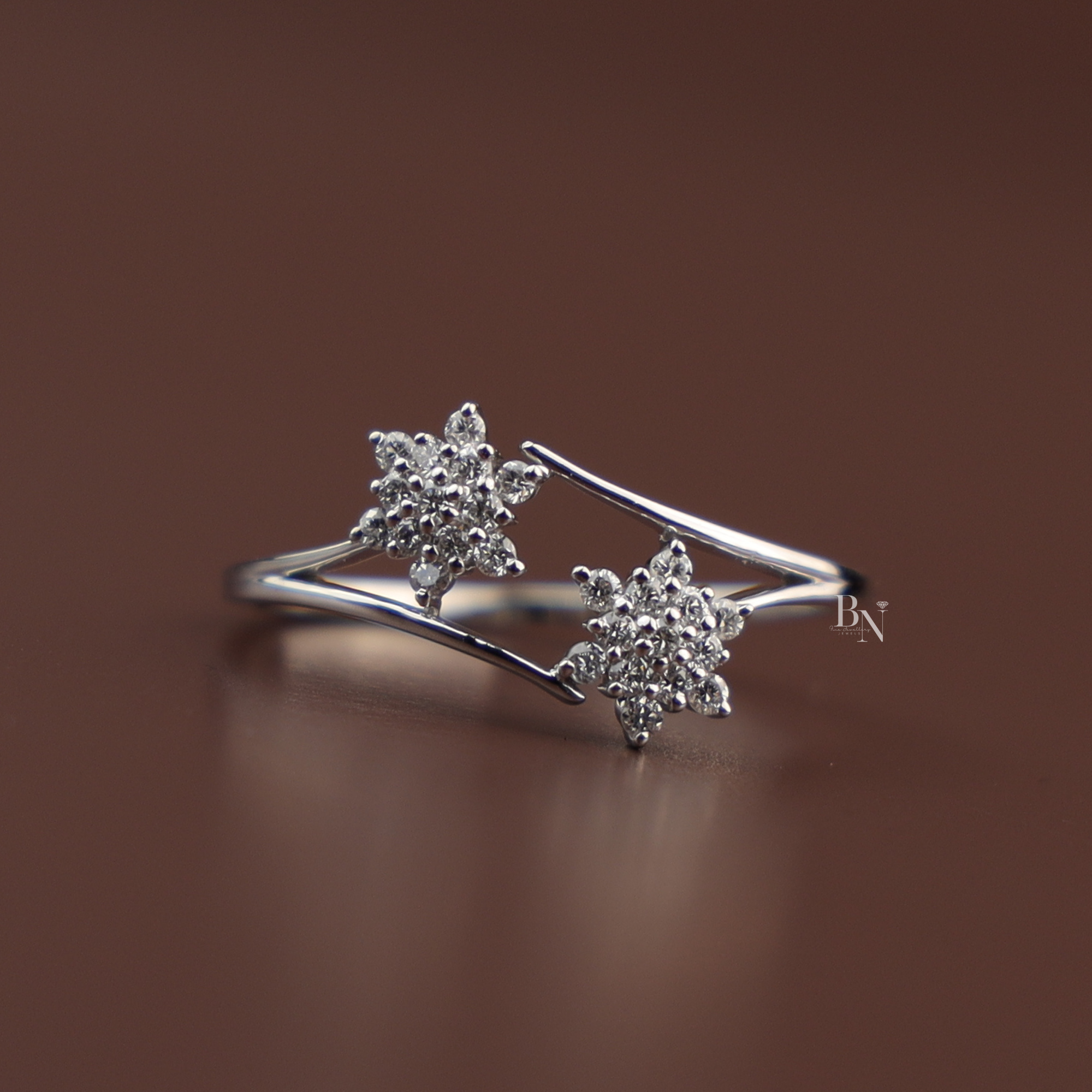 An elegant white gold open bypass ring featuring two sparkling round lab grown diamond star clusters on a delicate polished shank, viewed from multiple angles on a display and a hand.
