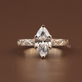 Detailed view of a 2 carat marquise lab grown diamond engagement ring with a vintage hand-engraved scroll band in 14k gold. Luxury bridal.