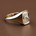 3 carat cushion cut lab grown diamond in a modern 14k yellow gold bezel signet setting on a hand, showing the high-polish tapered band and secure metal frame.
