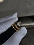 A modern 2 carat marquise lab diamond bridal set in yellow gold, held by gloved hands. The set includes a polished marquise solitaire and a unique matte-finish wedding band with spaced, flush-set IGI certified diamonds.