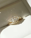 A woman's hand wearing a modern 2 carat East-West marquise lab diamond ring. The artistic bypass design in polished yellow gold wraps around the brilliant IGI certified diamond, creating a unique and minimalist statement.