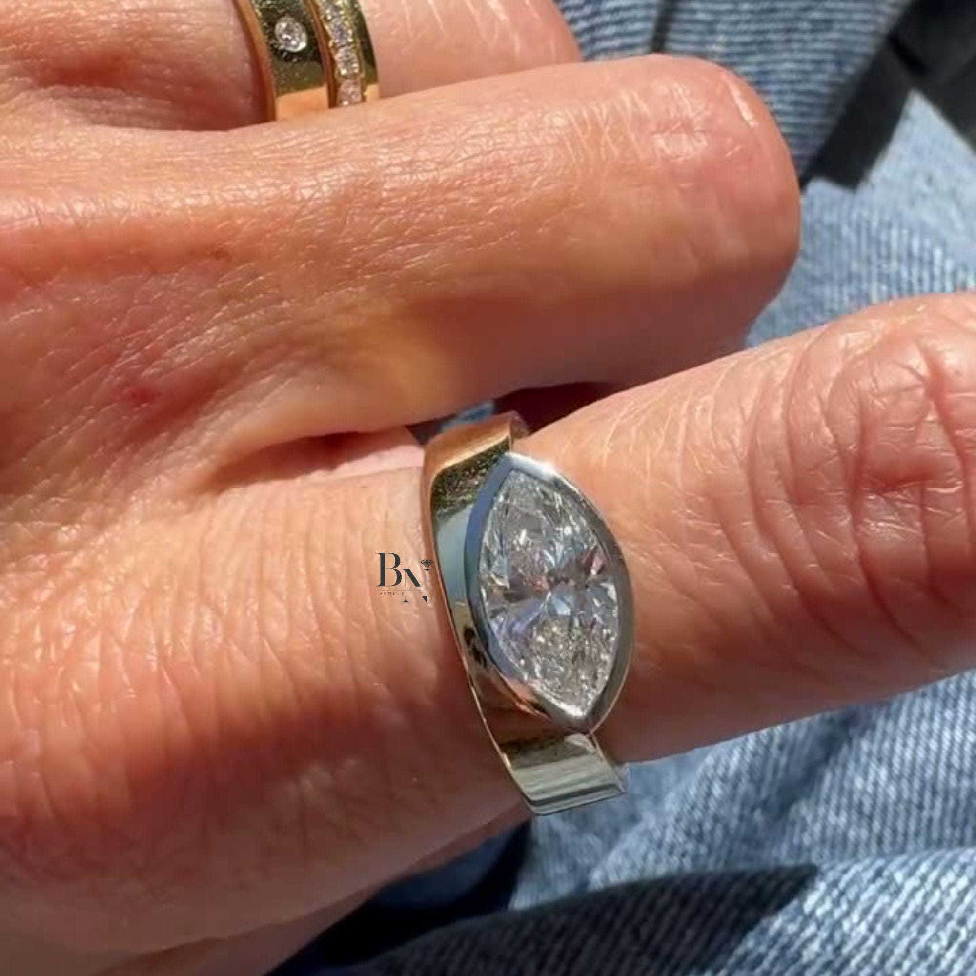 Luxurious 2 carat east-west marquise lab grown diamond engagement ring featuring a thick, wide cigar band in 14k yellow gold. Modern half-bezel horizontal setting.