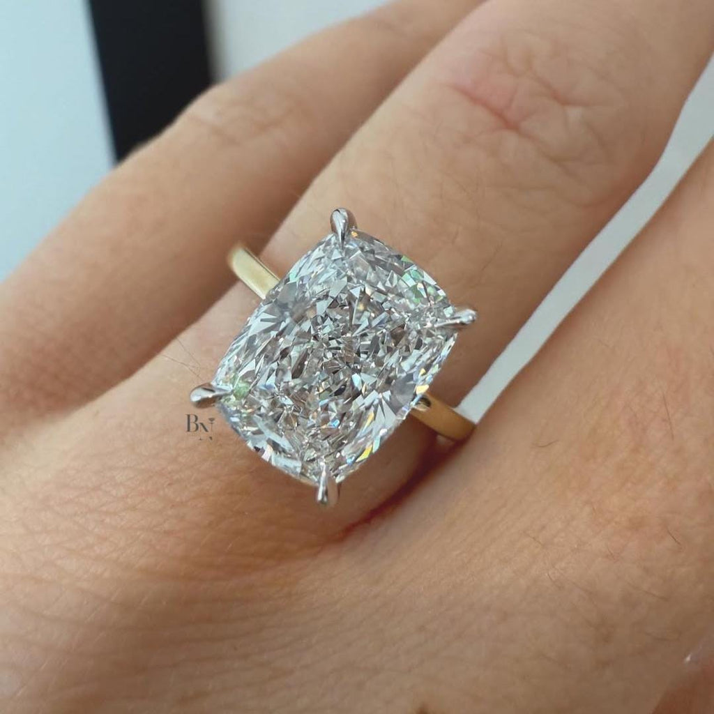 Hand shot of a 3 carat elongated cushion cut moissanite engagement ring with crushed ice effect, set in two-tone gold, showing high fire and maximum visual spread.